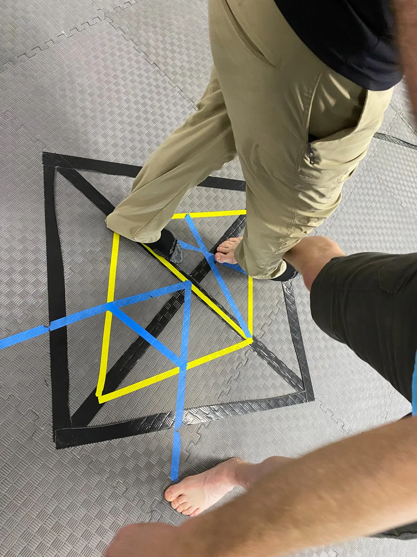 Taped triangles and Magen David geometry on a training floor beneath practitioners' feet